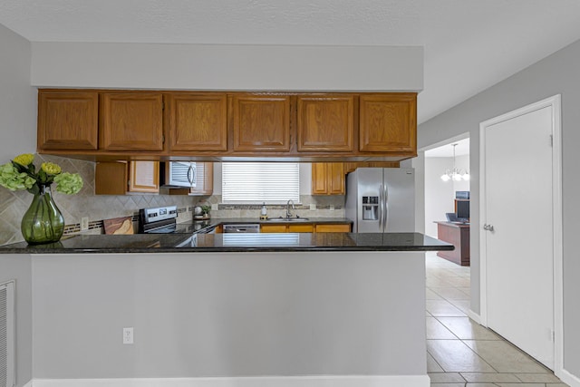 2526 Windswept Dr, Richmond, TX 77406 - kitchen featuring stainless steel appliances, a sink, a peninsula, and brown cabinets