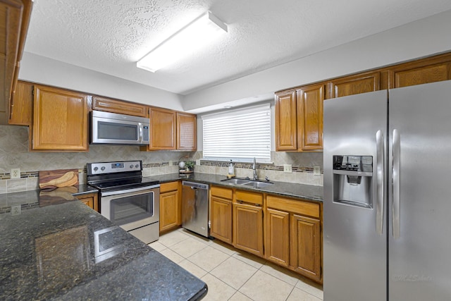 2526 Windswept Dr, Richmond, TX 77406 - kitchen featuring stainless steel appliances, a sink, tasteful backsplash, brown cabinetry, and a textured ceiling