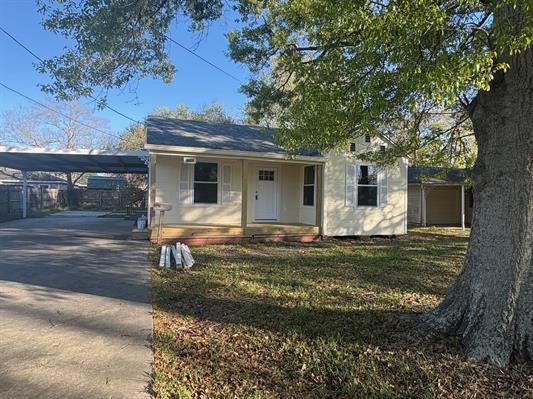6240 25th St, Groves, TX 77619 - view of front of home with concrete driveway, a porch, and a front lawn