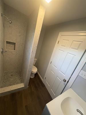 6240 25th St, Groves, TX 77619 - full bathroom featuring toilet, a shower stall, and wood finished floors