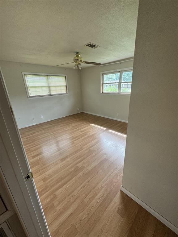 401 Henry St, Bridge City, TX 77611 - spare room with light wood-style flooring, ceiling fan, baseboards, and a textured ceiling