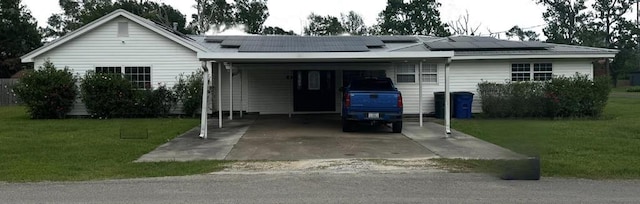 401 Henry St, Bridge City, TX 77611 - view of front of home featuring a front lawn, a carport, roof mounted solar panels, and driveway