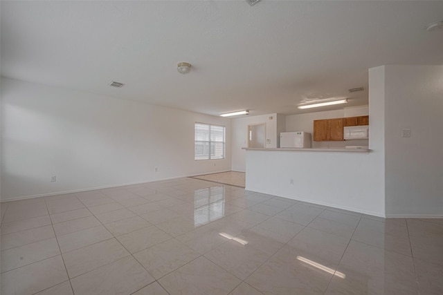 unfurnished living room featuring light tile patterned flooring and baseboards