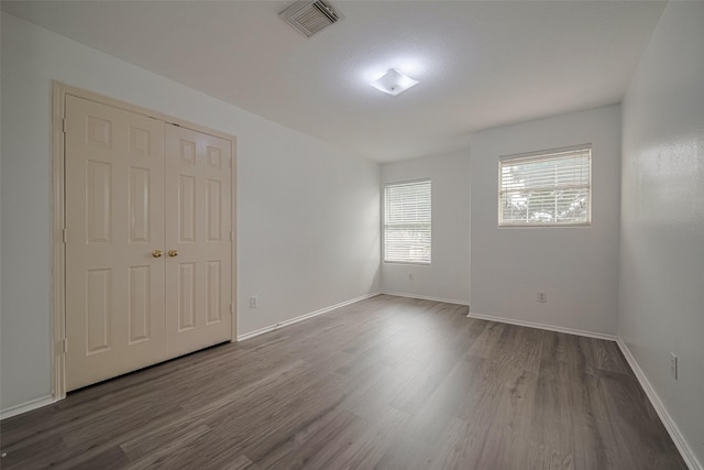 unfurnished bedroom with dark wood-type flooring, baseboards, and a closet