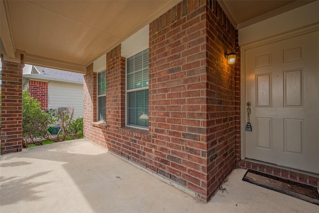 property entrance featuring brick siding and a porch