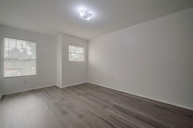 empty room featuring dark wood-style flooring and baseboards
