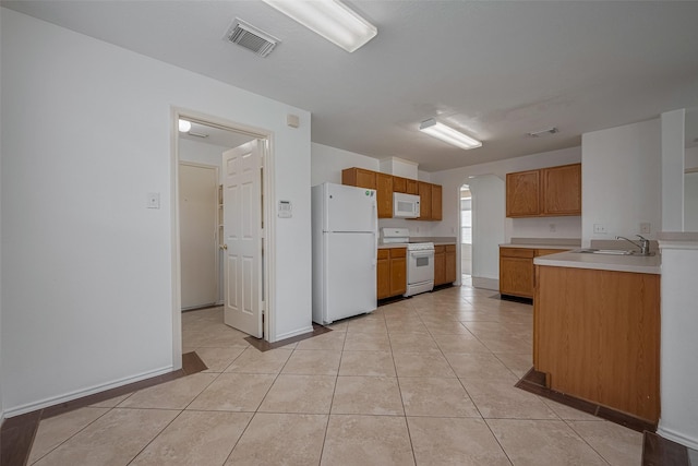 kitchen with white appliances, arched walkways, a sink, light countertops, and brown cabinets