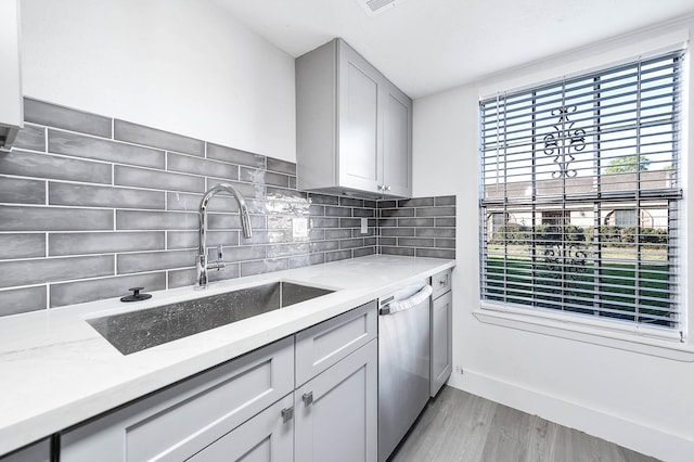7109 Chasewood Dr, Houston, TX 77489 - kitchen featuring stainless steel dishwasher, a sink, light wood finished floors, light stone countertops, and decorative backsplash