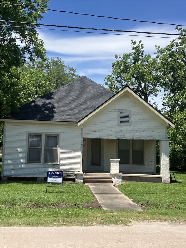 1401 8th St, Bay City, TX 77414 - bungalow-style home with a front yard, roof with shingles, and covered porch