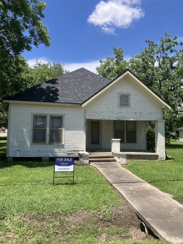1401 8th St, Bay City, TX 77414 - bungalow-style house with a front lawn, roof with shingles, and a porch