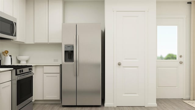 281 Douglas Hills Dr, Magnolia, TX 77354 - kitchen with stainless steel appliances, light countertops, light wood-style flooring, and white cabinets