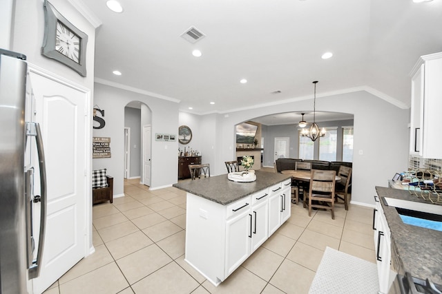 419 Sunny River Ln, Richmond, TX 77406 - kitchen featuring arched walkways, stainless steel fridge, ornamental molding, light tile patterned flooring, and a chandelier