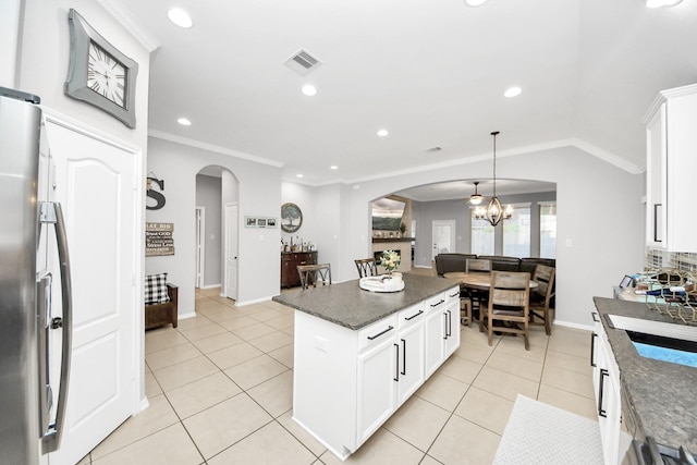 419 Sunny River Ln, Richmond, TX 77406 - kitchen featuring arched walkways, a chandelier, freestanding refrigerator, crown molding, and light tile patterned floors