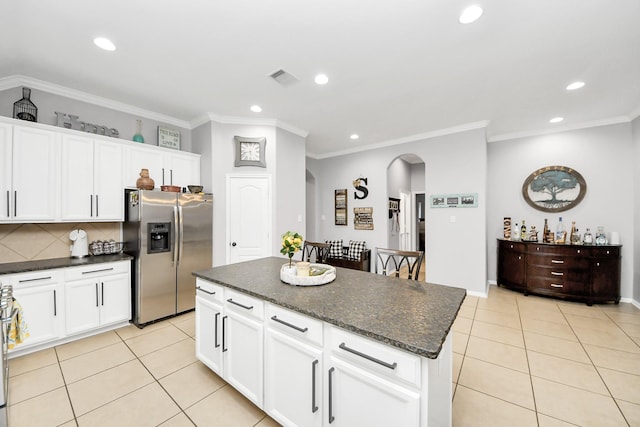 419 Sunny River Ln, Richmond, TX 77406 - kitchen with stainless steel fridge, arched walkways, light tile patterned floors, recessed lighting, and white cabinets