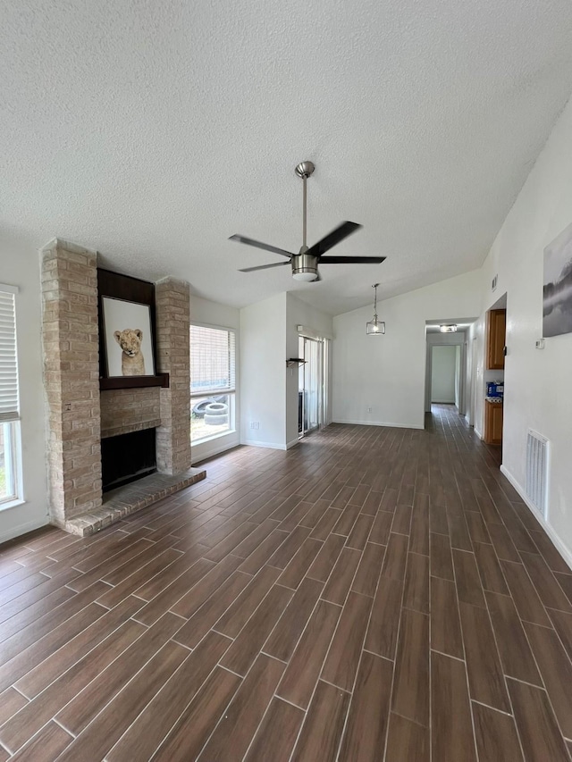 6343 Glenhagen Dr, Houston, TX 77084 - unfurnished living room featuring a textured ceiling, ceiling fan, lofted ceiling, dark wood-style floors, and a fireplace