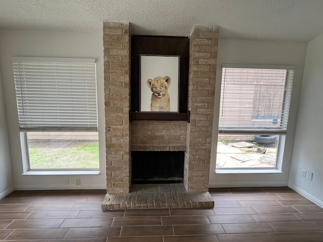 6343 Glenhagen Dr, Houston, TX 77084 - unfurnished living room featuring wood tiled floors, a textured ceiling, a brick fireplace, and baseboards