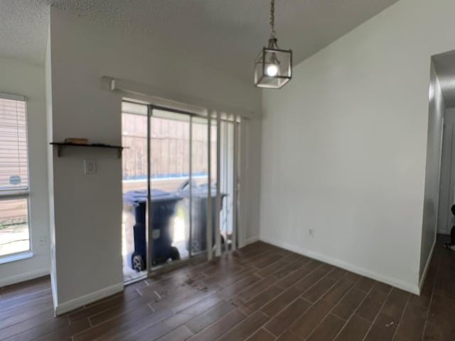 6343 Glenhagen Dr, Houston, TX 77084 - unfurnished dining area with dark wood-style flooring, baseboards, plenty of natural light, and a textured ceiling