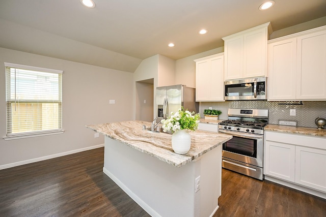 10130 Barn Owl Trl, Magnolia, TX 77354 - kitchen with stainless steel appliances, backsplash, a center island with sink, light stone counters, and baseboards