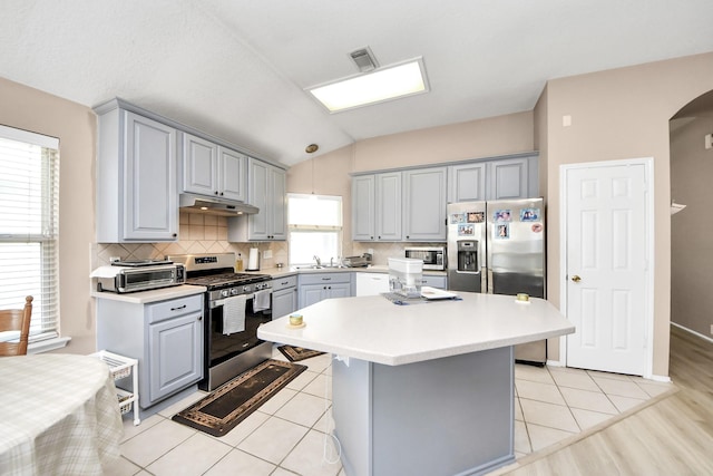 11843 Leaf Oak Dr, Houston, TX 77065 - kitchen featuring stainless steel appliances, gray cabinets, under cabinet range hood, light countertops, and lofted ceiling