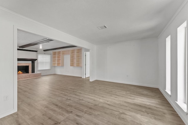 563 Roanoke Dr, Conroe, TX 77302 - unfurnished living room with wood finished floors, crown molding, baseboards, a warm lit fireplace, and beam ceiling
