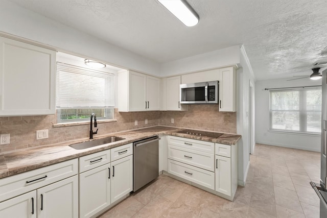 563 Roanoke Dr, Conroe, TX 77302 - kitchen with a sink, appliances with stainless steel finishes, backsplash, white cabinetry, and a textured ceiling