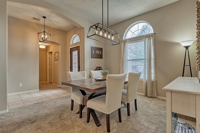 dining area featuring arched walkways, light colored carpet, baseboards, a chandelier, and light tile patterned floors
