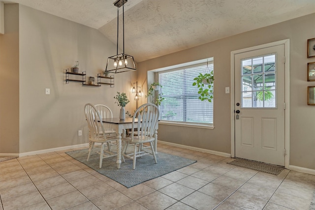 dining room with healthy amount of natural light, light tile patterned floors, vaulted ceiling, a chandelier, and baseboards