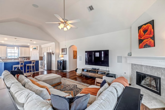 2101 Menard Ave, Seabrook, TX 77586 - living room featuring dark wood finished floors, vaulted ceiling, arched walkways, a ceiling fan, and a fireplace
