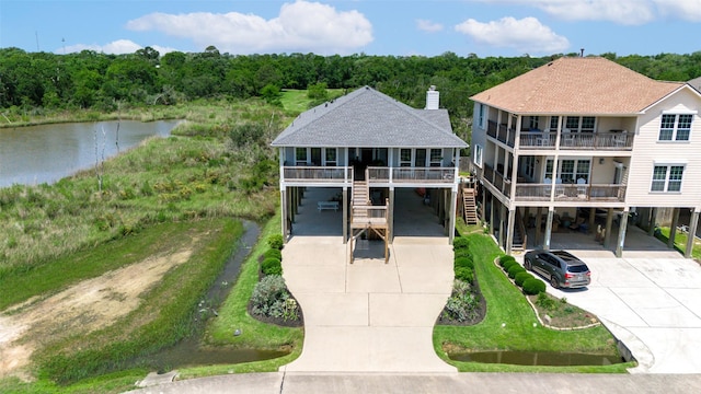 2101 Menard Ave, Seabrook, TX 77586 - view of front facade with concrete driveway, a carport, a water view, stairs, and roof with shingles