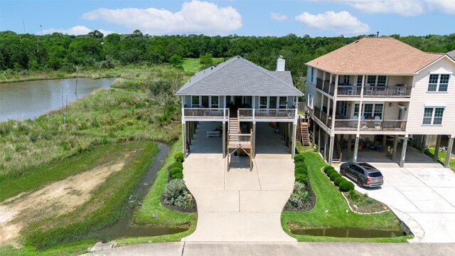 2101 Menard Ave, Seabrook, TX 77586 - view of front of home featuring concrete driveway, a carport, a water view, stairway, and roof with shingles