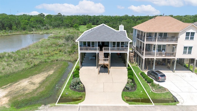 2101 Menard Ave, Seabrook, TX 77586 - view of front of house featuring a carport, driveway, a water view, a chimney, and roof with shingles