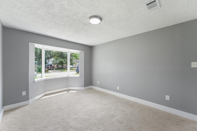 carpeted empty room featuring a textured ceiling and baseboards