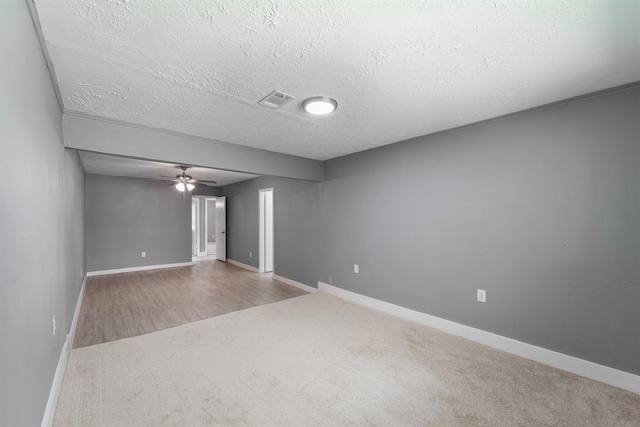 carpeted spare room featuring a textured ceiling, baseboards, and a ceiling fan