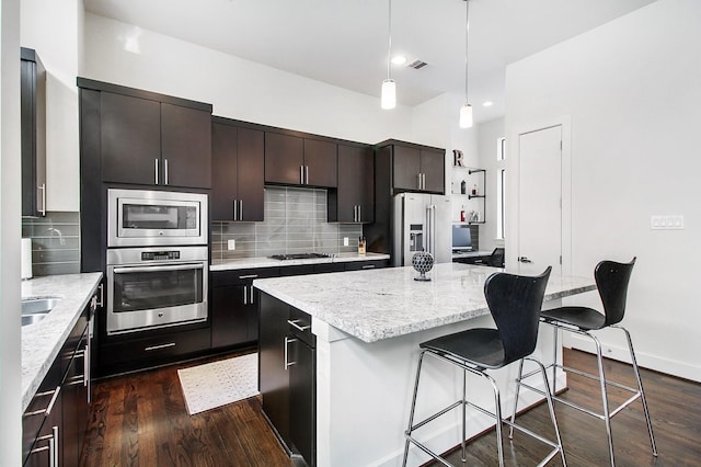 2205 Colorado St, Houston, TX 77007 - kitchen with stainless steel appliances, a kitchen island, dark wood-type flooring, a breakfast bar area, and backsplash
