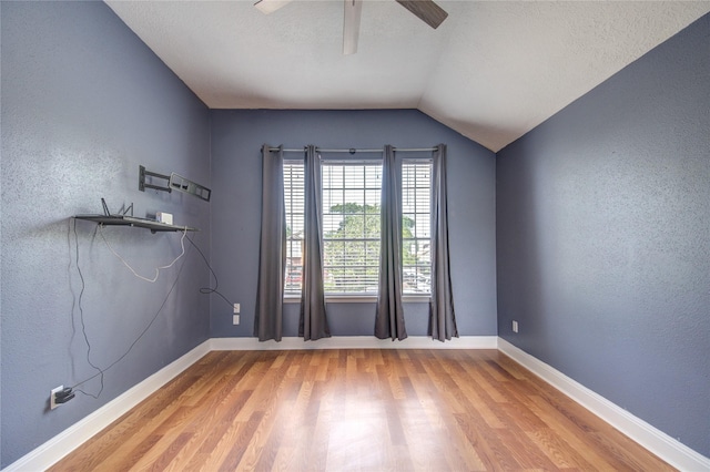 unfurnished room featuring light wood-style flooring, ceiling fan, baseboards, lofted ceiling, and a textured ceiling