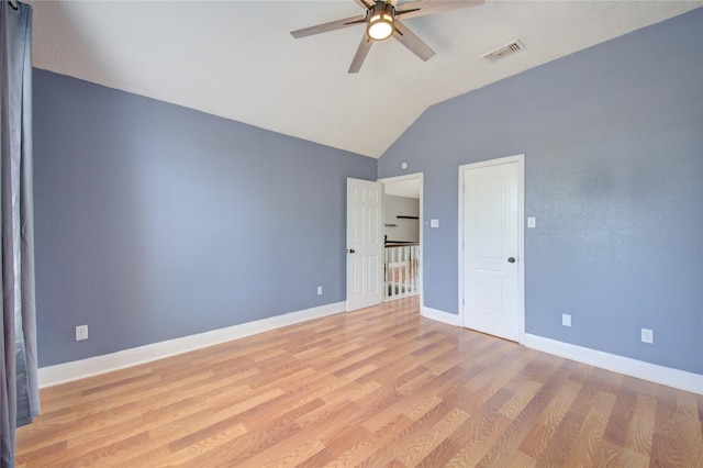 empty room featuring lofted ceiling, ceiling fan, light wood-style floors, and baseboards
