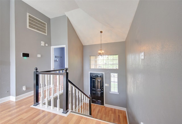 entrance foyer featuring high vaulted ceiling, wood finished floors, a chandelier, and baseboards