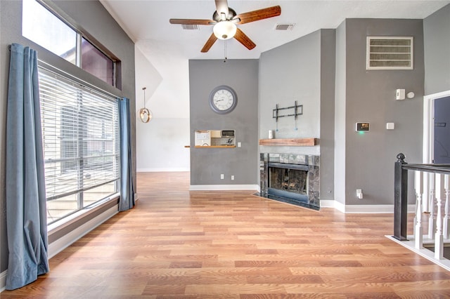 living area featuring a ceiling fan, healthy amount of natural light, a high ceiling, and baseboards