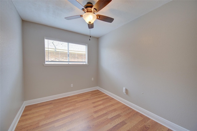 spare room with light wood-type flooring, a ceiling fan, and baseboards
