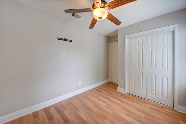 unfurnished bedroom featuring light wood-style floors, a closet, baseboards, and ceiling fan