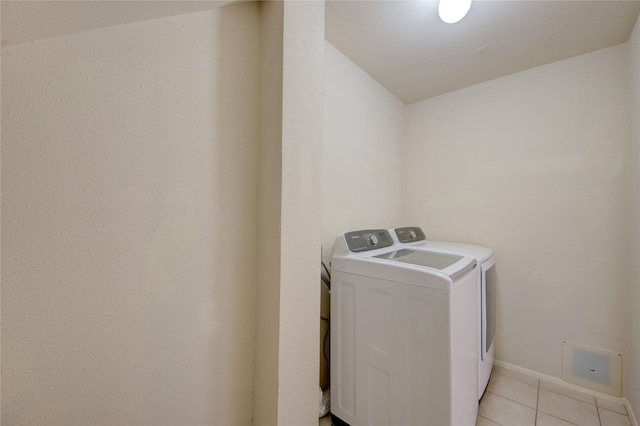 laundry room featuring washing machine and dryer, light tile patterned floors, and baseboards