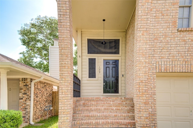 entrance to property with a garage and brick siding