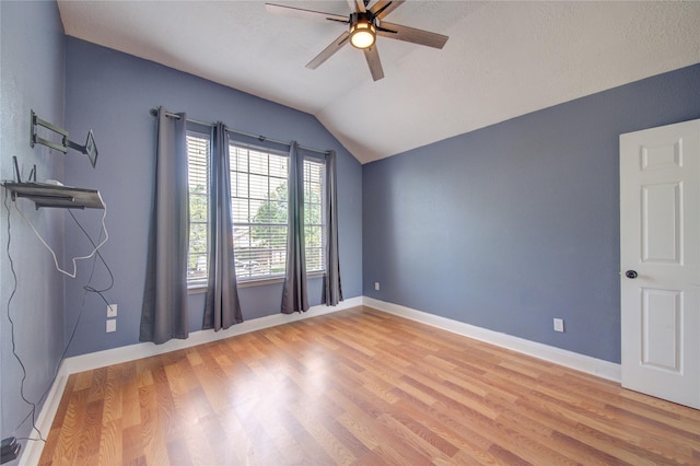 unfurnished room featuring vaulted ceiling, a ceiling fan, light wood-style flooring, baseboards, and a textured ceiling