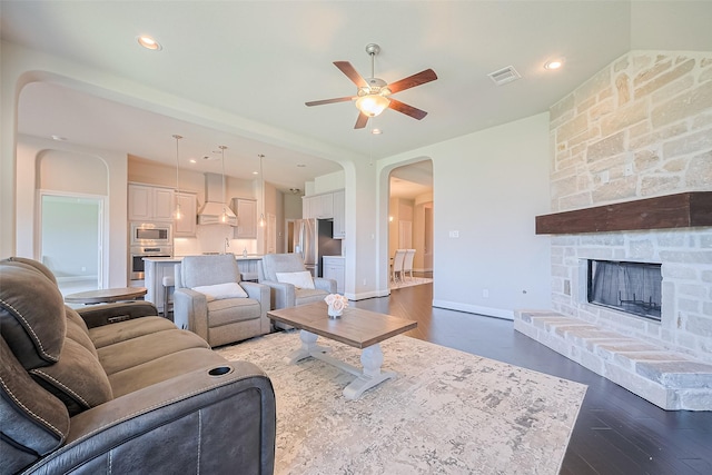 living room featuring arched walkways, a ceiling fan, dark wood-style flooring, baseboards, and recessed lighting