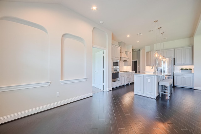 kitchen featuring appliances with stainless steel finishes, light countertops, a kitchen bar, lofted ceiling, and a sink