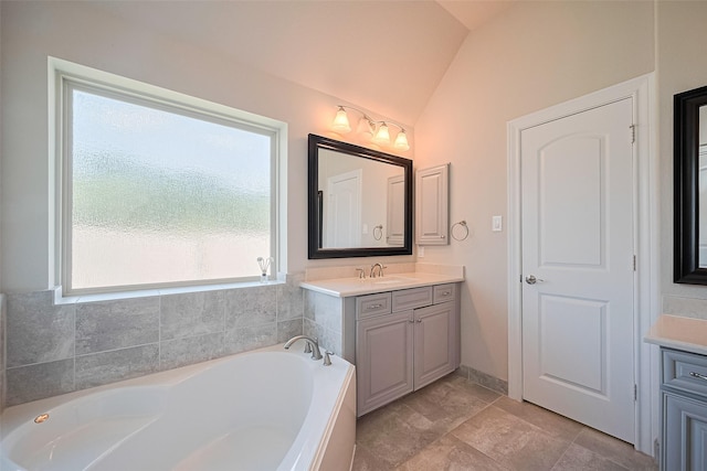 bathroom with vanity, vaulted ceiling, and a garden tub