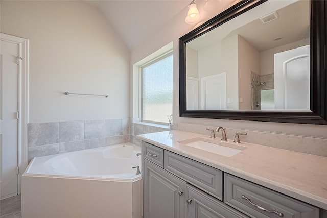 bathroom with vanity, a garden tub, and vaulted ceiling