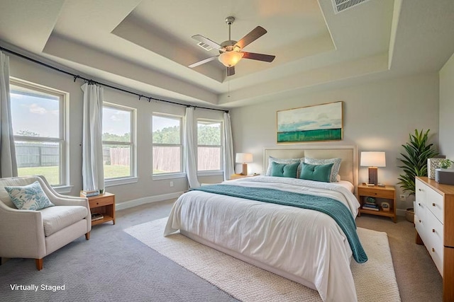 bedroom with a raised ceiling, light carpet, baseboards, and ceiling fan