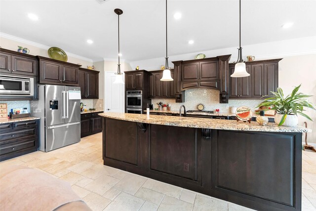 222 Reynosa Ct, Pinehurst, TX 77362 - kitchen featuring appliances with stainless steel finishes, decorative backsplash, dark brown cabinets, a large island with sink, and crown molding