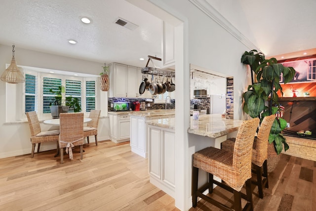 6206 Bayou Blvd, Baytown, TX 77521 - kitchen with light wood finished floors, decorative backsplash, light stone countertops, recessed lighting, and a breakfast bar